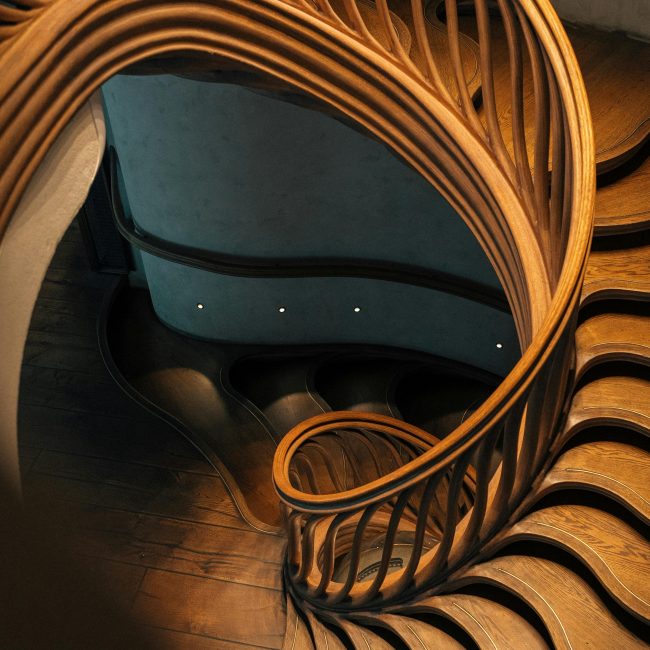 A mesmerizing spiral staircase featuring elegant wooden balustrades in a modern London interior. Un escalier en spirale captivant présentant d'élégantes balustrades en bois dans un intérieur moderne londonien.