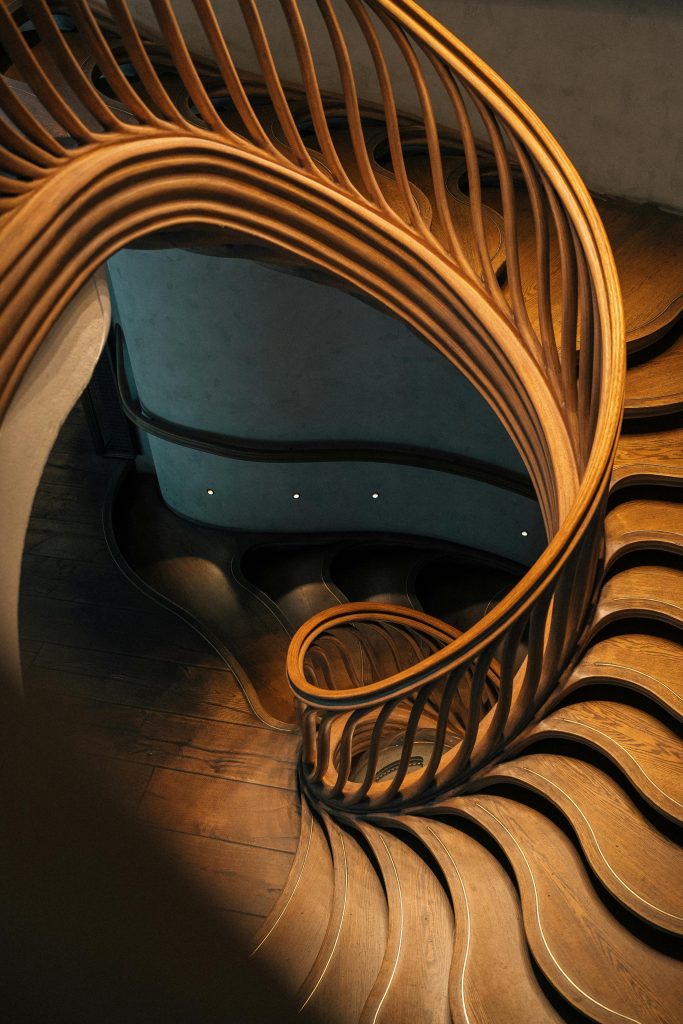 A mesmerizing spiral staircase featuring elegant wooden balustrades in a modern London interior. Un escalier en spirale captivant présentant d'élégantes balustrades en bois dans un intérieur moderne londonien.