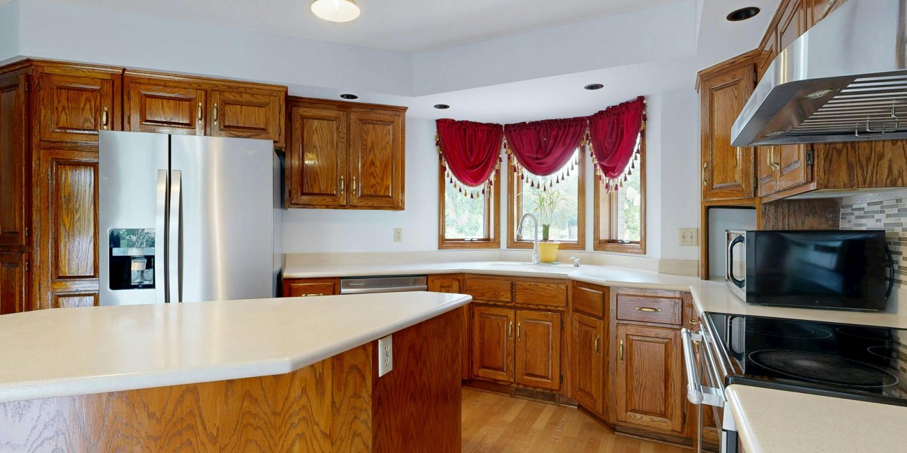 A bright, modern kitchen featuring wooden cabinets, island, and stainless steel appliances. Une cuisine moderne et lumineuse avec des armoires en bois, un îlot et des appareils en acier inoxydable.