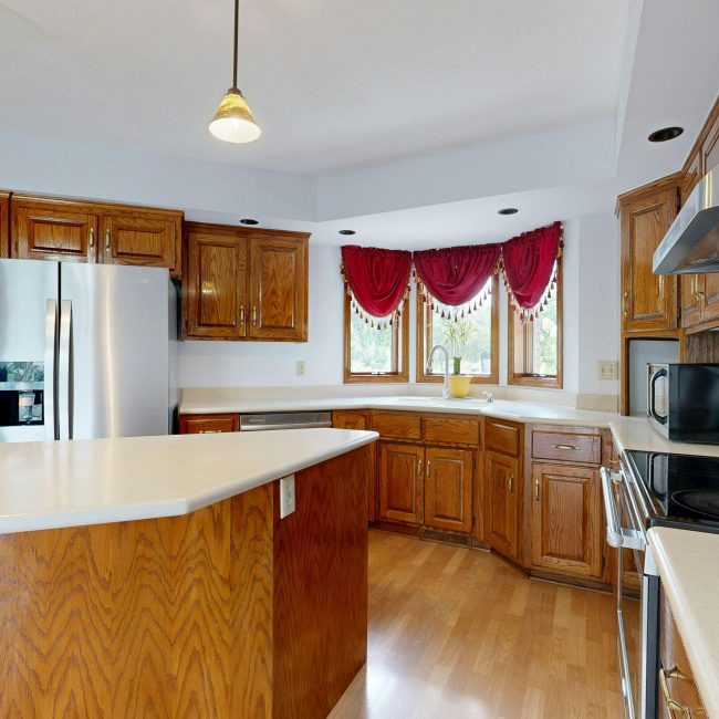 A bright, modern kitchen featuring wooden cabinets, island, and stainless steel appliances. Une cuisine moderne et lumineuse avec des armoires en bois, un îlot et des appareils en acier inoxydable.