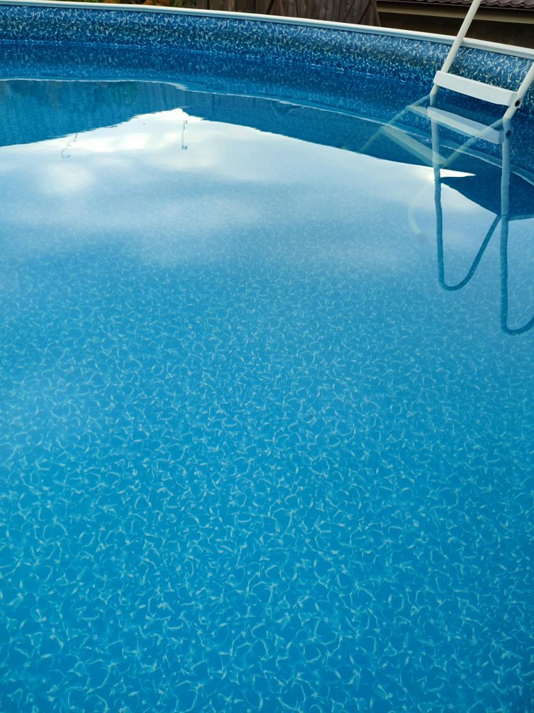 Captivating view of a blue swimming pool with a ladder reflected on the surface, ideal summer relaxation spot. Vue captivante d'une piscine bleue avec une échelle reflétée à la surface, un endroit idéal pour la détente estivale.