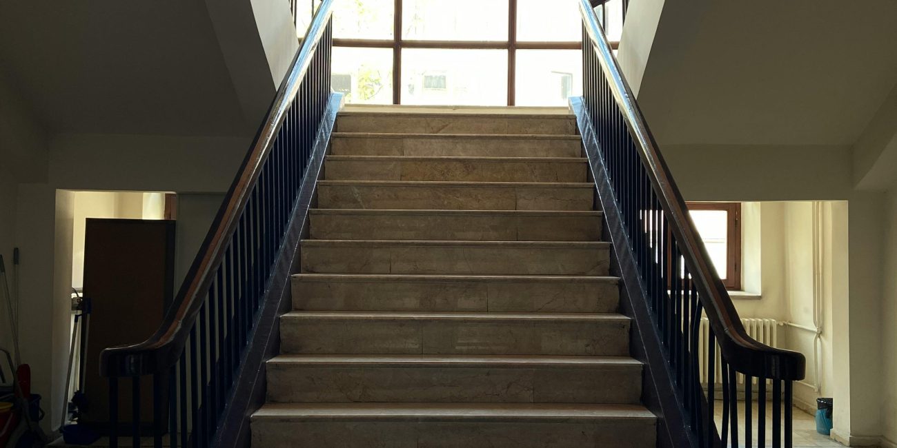 A beautifully lit bifurcated staircase with marble steps and wooden handrails in Ankara, Türkiye. Un escalier bifurqué magnifiquement éclairé avec des marches en marbre et des mains courantes en bois à Ankara, Türkiye.
