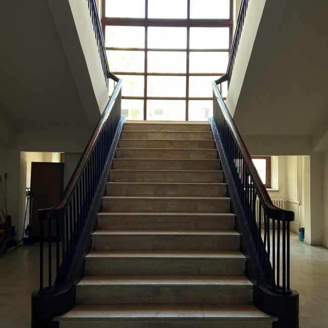 A beautifully lit bifurcated staircase with marble steps and wooden handrails in Ankara, Türkiye. Un escalier bifurqué magnifiquement éclairé avec des marches en marbre et des mains courantes en bois à Ankara, Türkiye.