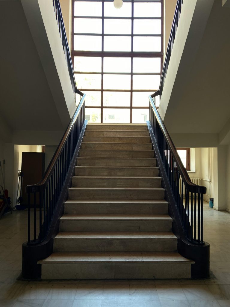A beautifully lit bifurcated staircase with marble steps and wooden handrails in Ankara, Türkiye. Un escalier bifurqué magnifiquement éclairé avec des marches en marbre et des mains courantes en bois à Ankara, Türkiye.
