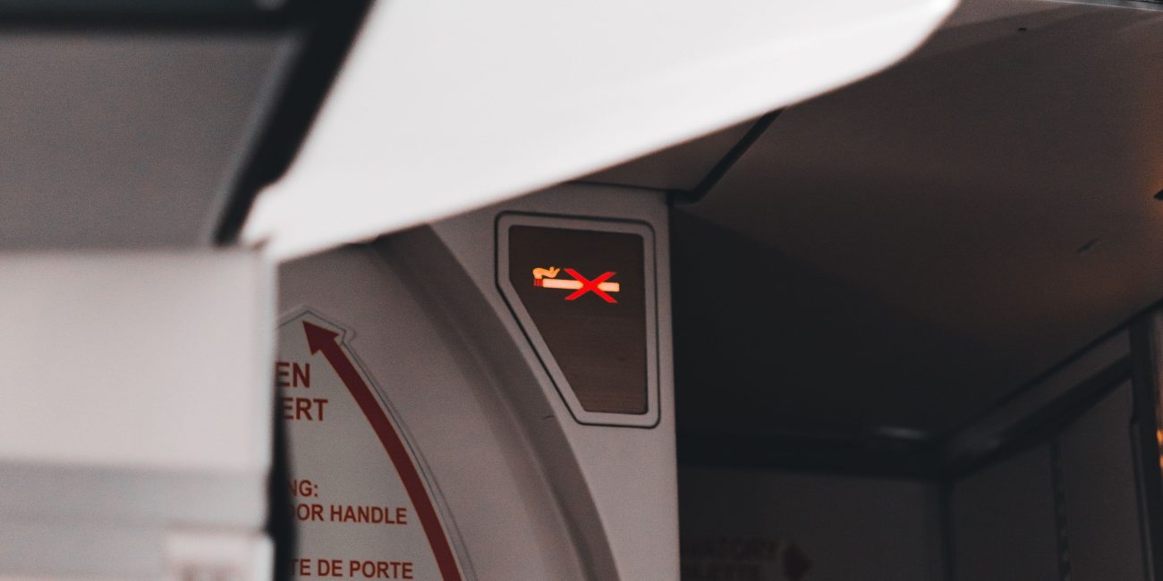 Close-up of an airplane exit door and illuminated sign, capturing the cabin atmosphere. Gros plan sur la porte de sortie d'un avion et le panneau illuminé, capturant l'atmosphère de la cabine.