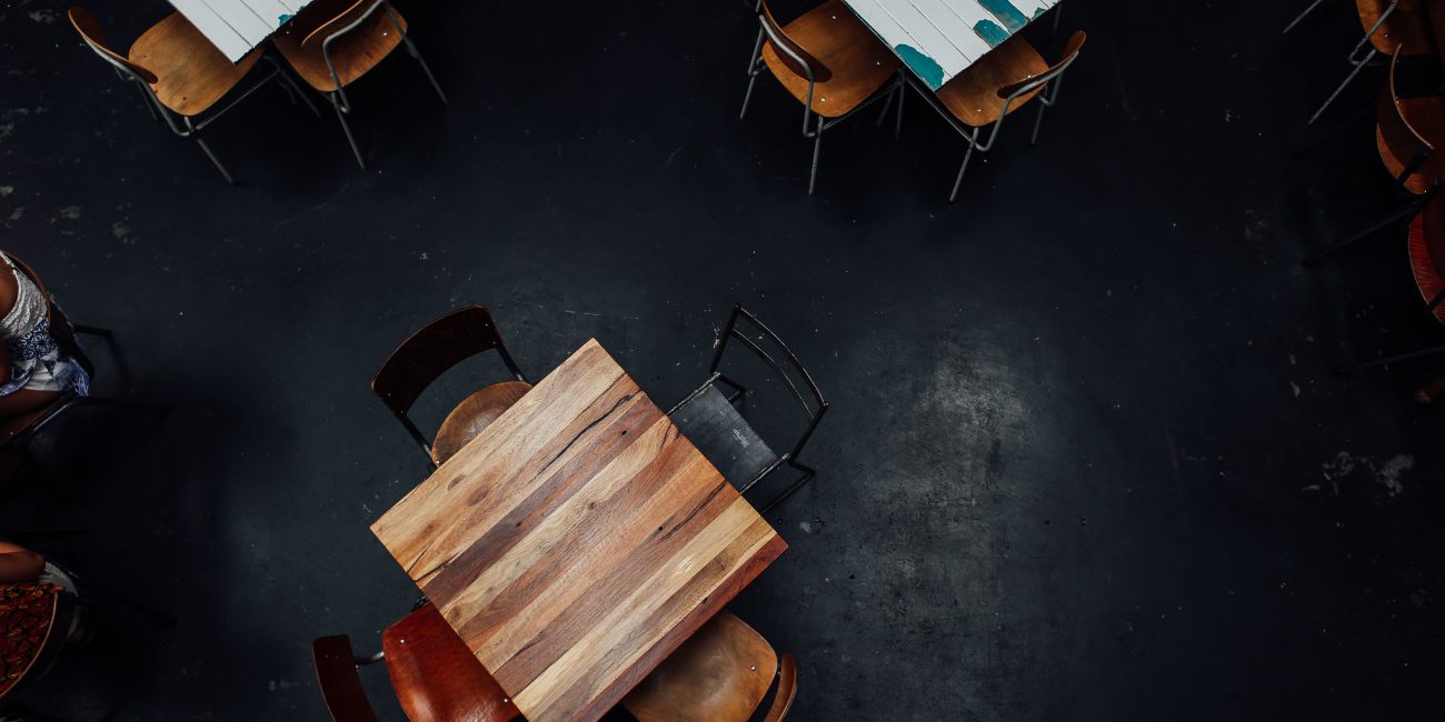Aerial shot of rustic wooden tables and chairs in a dimly lit restaurant setting. Vue aérienne de tables et chaises en bois rustique dans un restaurant faiblement éclairé.