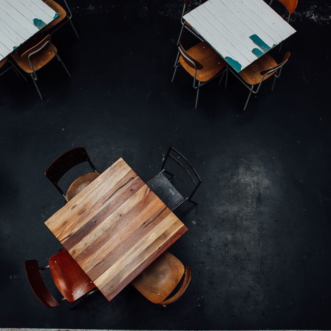Aerial shot of rustic wooden tables and chairs in a dimly lit restaurant setting. Vue aérienne de tables et chaises en bois rustique dans un restaurant faiblement éclairé.