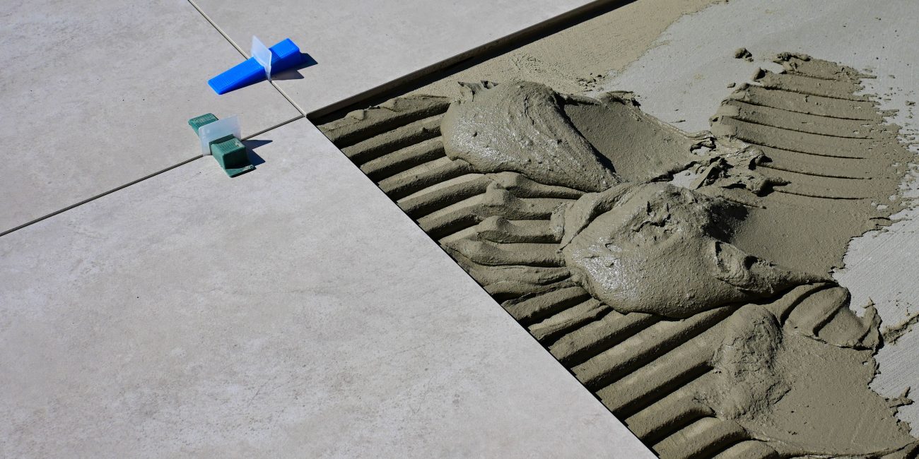 Close-up of wet cement and tile spacers during floor tile installation. Gros plan sur du ciment mouillé et des entretoises de carrelage lors de l'installation de carrelage de sol.