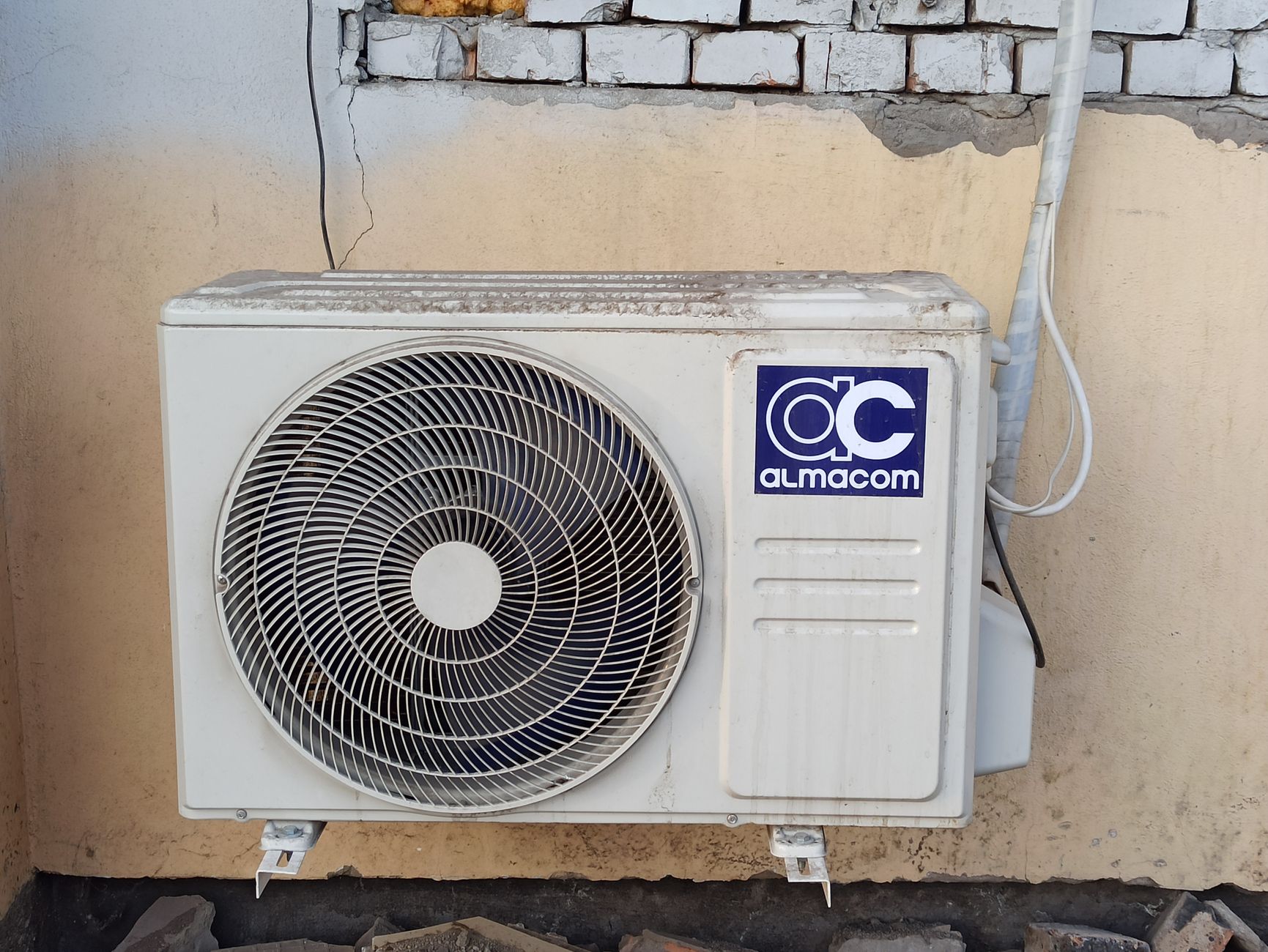 Unité extérieure de climatisation fixée sur un mur en briques