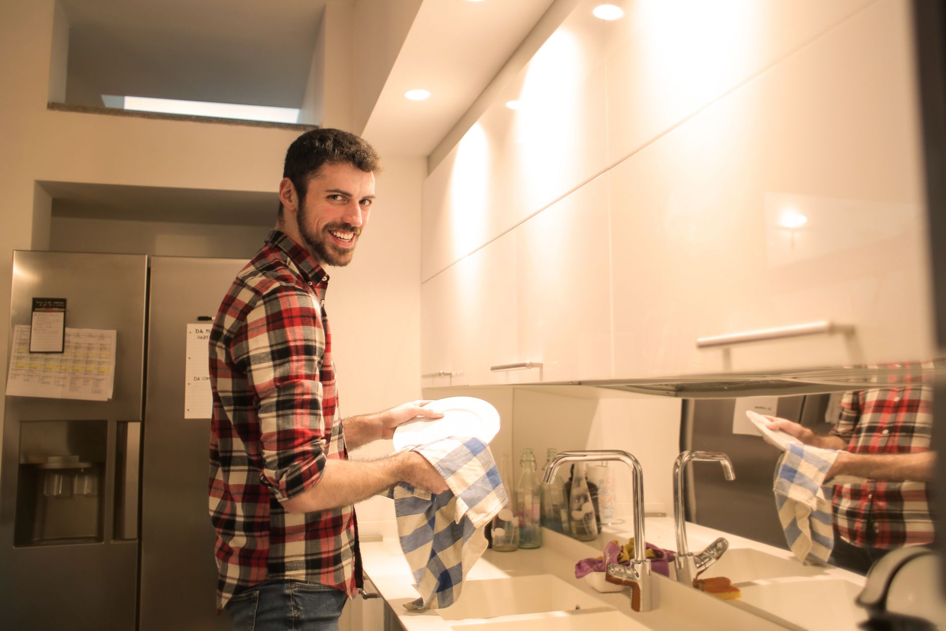 Homme qui nettoie de la vaisselle dans une cuisine claire